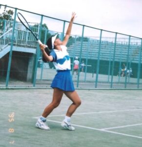 学生時代の靖代さんがテニスサーブを打つ姿