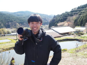 笑顔でカメラを持つ奥村さん