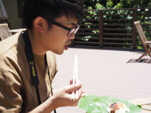 お箸で朴葉寿司を食べるヤマモト
