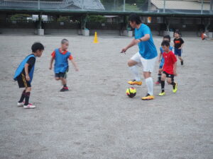 サッカースクールで子どもたちと一緒にプレーする浅井さん