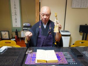 『梅花流詠讃歌』で使う道具の説明をしてくれる加納さん
