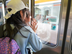 車窓からすれ違う電車に向かって手を振る子どもたち