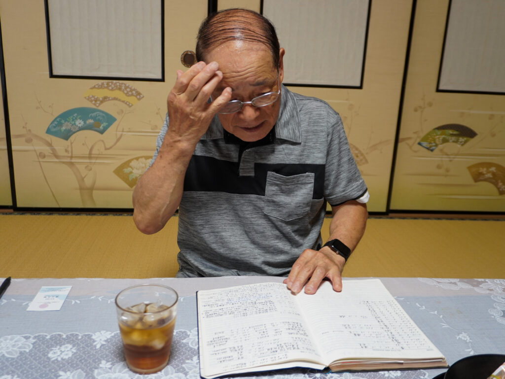これまでの役や経歴をまとめたノートを確認する博幸さん